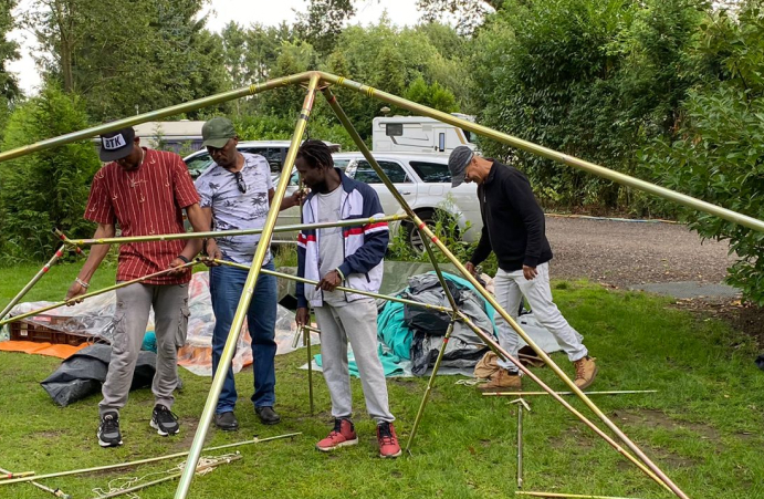 3 mensen die een frame van tent in elkaar zetten